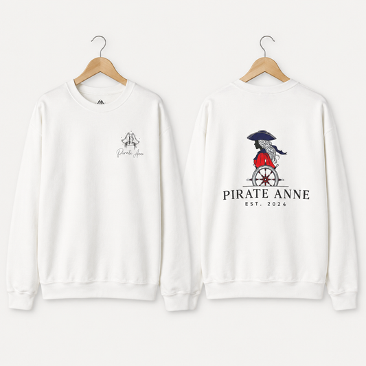 Two white crewneck sweatshirts on wooden hangers, showing the front and back designs. The front has a small black graphic on the left chest, and the back features a larger graphic of a pirate riding a cart with the text 'PIRATE ANNE EST.